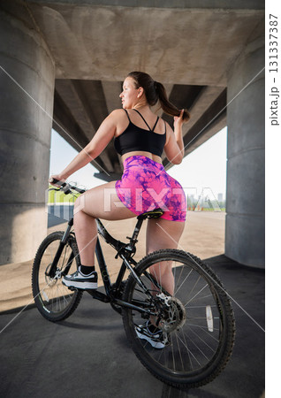 Caucasian woman in short shorts riding a bicycle.  131337387