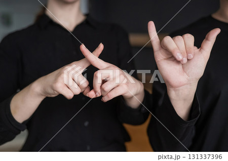 A man and a woman show the phrase technical university in sign language. A man and a woman show the phrase technical university in sign language. 131337396