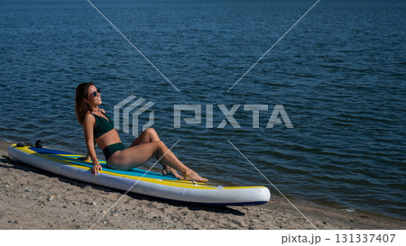 Caucasian woman posing on a SUP board. Summer sport. Caucasian woman posing on a SUP board. Summer sport. 131337407