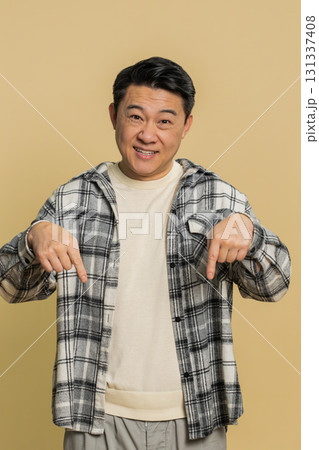Asian blogger man pointing down, saying to subscribe gesturing ok like showing place for information Asian blogger man pointing down, saying to subscribe gesturing ok like showing place for information 131337408