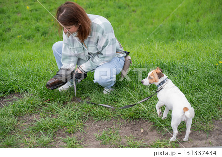 A woman cleans up dog excrement while on a walk. 131337434