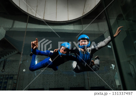 A male instructor teaches a woman how to fly in a wind tunnel. Free fall simulator. A male instructor teaches a woman how to fly in a wind tunnel. Free fall simulator. 131337497