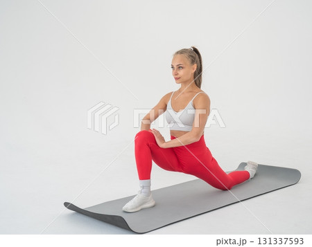 Young woman doing splits exercises on white background. Young woman doing splits exercises on white background. 131337593