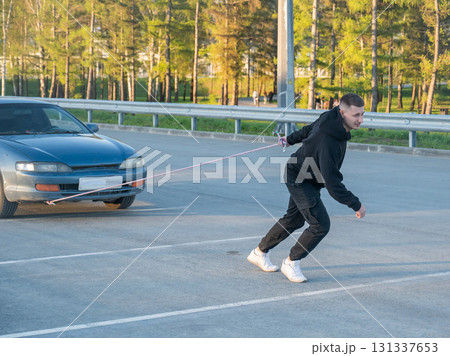 Caucasian man pulling a car with a rope.  131337653