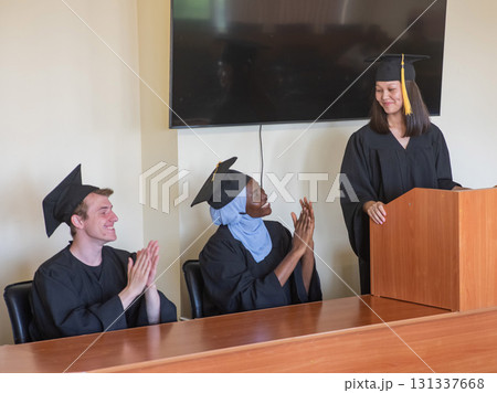 A young woman stands at the lectern and delivers a graduation speech to her classmates. A young woman stands at the lectern and delivers a graduation speech to her classmates. 131337668