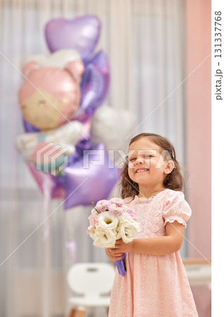 Cute little child girl in pink dress with flowers and pink purple balloons. Birthday concept. Cute little child girl in pink dress with flowers and pink purple balloons. Birthday concept. 131337768