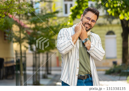 Caucasian young man feeling toothache bad unpleasant symptoms suffering from pain standing on street 131338135