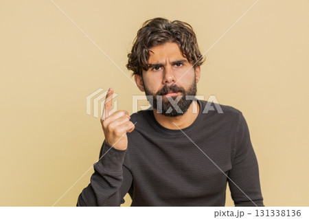 Displeased young Hindu man gesturing hands with irritation and displeasure against beige background 131338136
