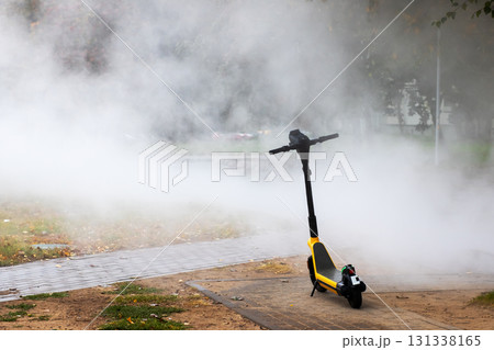 A yellow and black scooter is enveloped by a thick cloud of smoke A yellow and black scooter is enveloped by a thick cloud of smoke 131338165