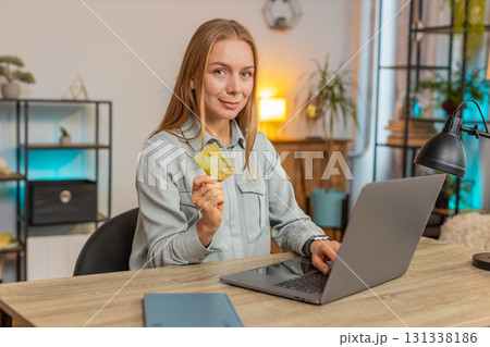 Happy Caucasian woman freelancer using credit card and laptop for online shopping at table at home 131338186