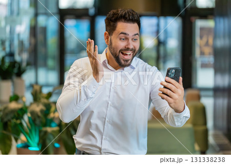 Happy young businessman using smartphone shocked by sudden victory lottery win in office lobby 131338238