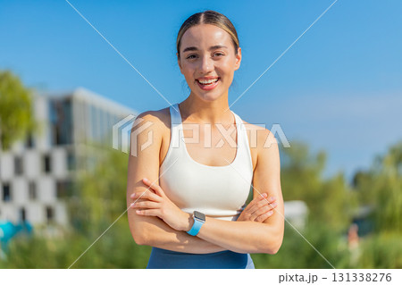 Portrait of happy Caucasian young sporty woman in activewear standing arms crossed in city park 131338276