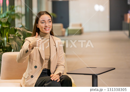 Portrait of smiling Caucasian young businesswoman girl in formal showing thumb up in hotel lobby Portrait of smiling Caucasian young businesswoman girl in formal showing thumb up in hotel lobby 131338305
