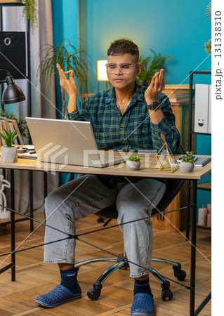 Indian man working on laptop eyes closed meditating concentrated thoughts taking a break relaxing Indian man working on laptop eyes closed meditating concentrated thoughts taking a break relaxing 131338310