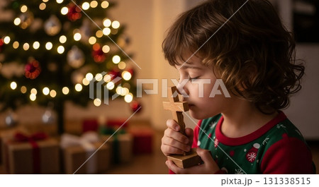 A child holding a candle near a Christmas tree. 131338515