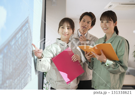 スクリーンの前で建設の打ち合わせをする3人の男女 131338621