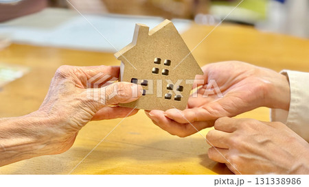 家の小物を女性に渡す高齢女性_テーブル背景 家の小物を女性に渡す高齢女性_テーブル背景 131338986