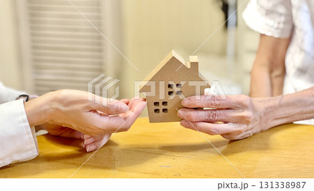 家の小物を女性に渡す高齢女性_リビング背景 家の小物を女性に渡す高齢女性_リビング背景 131338987