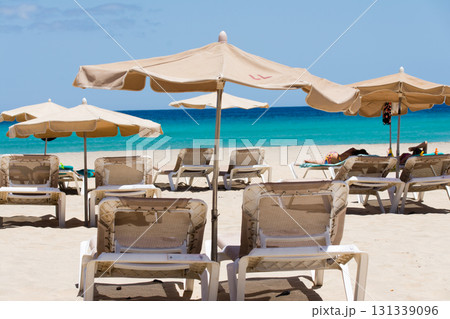 青空と明るい強い日差しの下の砂浜に並べられたビーチベッドとパラソル　フエルテベンテュラ島にて 131339096