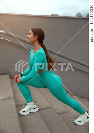 Portrait of fit and sporty young woman doing stretching in city. Beautiful fitness athlete woman. 131340030