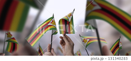 Zimbabwe flags in their hands on a blurred urban background 131340283