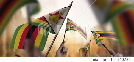 Zimbabwe flags in their hands on a blurred urban background 131340286