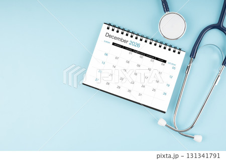 December 2026 desk calendar and stethoscope on blue color, Position with copy space. December 2026 desk calendar and stethoscope on blue color, Position with copy space. 131341791