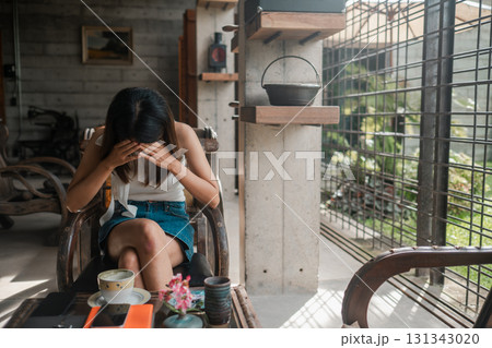 Woman sitting in a modern cafe, enjoying coffee and using a smartphone, surrounded by natural light and contemporary decor. Woman sitting in a modern cafe, enjoying coffee and using a smartphone, surrounded by natural light and contemporary decor. 131343020