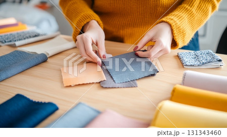 Fashion designer selecting fabric samples for new clothing collection, working at a desk with various colorful textiles and materials, creating stylish and trendy garments Fashion designer selecting fabric samples for new clothing collection, working at a desk with various colorful textiles and materials, creating stylish and trendy garments 131343460