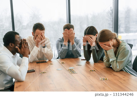 Covering eyes with hands. Playing card game. Team of office workers are together indoors 131344246