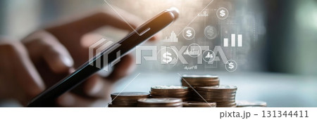 Businessman is using smartphone for managing finances and investments with growing coins stack and financial graph, representing online banking, saving money, and financial technology concept Businessman is using smartphone for managing finances and investments with growing coins stack and financial graph, representing online banking, saving money, and financial technology concept 131344411