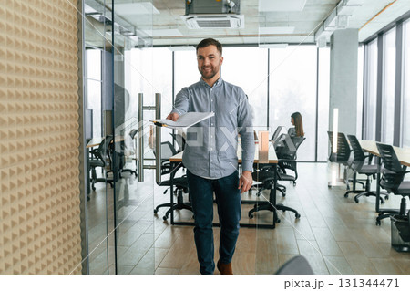 Handsome man with documents. Team of office workers are together indoors 131344471