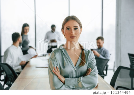 Beautiful young woman is standing if from of her colleagues. Team of office workers are together indoors 131344494