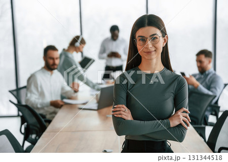 Young woman in glasses, portrait. Team of office workers are together indoors Young woman in glasses, portrait. Team of office workers are together indoors 131344518