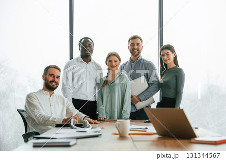 Posing for the camera. Team of office workers are together indoors Posing for the camera. Team of office workers are together indoors 131344567