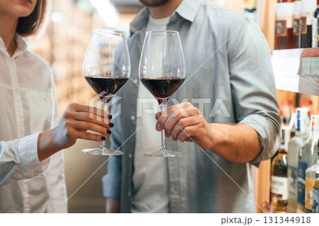 Glasses with drink. Take a sample. Man and woman are choosing wine in the shop 131344918