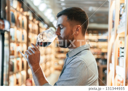 Drink tasting. Man is choosing wine in the store Drink tasting. Man is choosing wine in the store 131344935