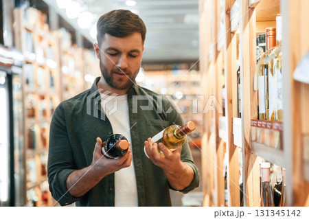 Front view. Man is choosing wine in the store 131345142