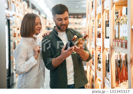 Choosing between two different bottles. Man and woman in the wine shop 131345327