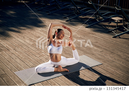 On the yoga mat. Young woman in fitness clothes is outdoors On the yoga mat. Young woman in fitness clothes is outdoors 131345417