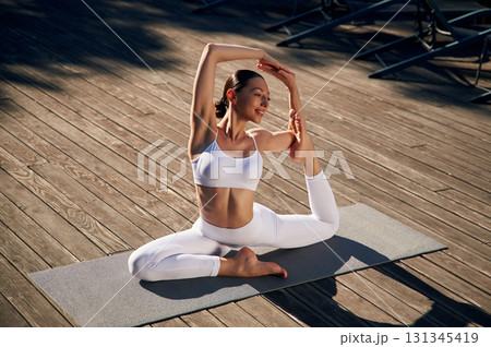 On the yoga mat. Young woman in fitness clothes is outdoors On the yoga mat. Young woman in fitness clothes is outdoors 131345419