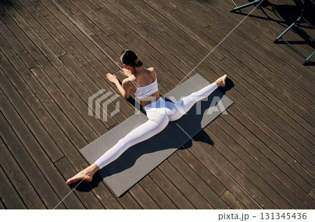 Stretching the legs. Young woman in fitness clothes is outdoors Stretching the legs. Young woman in fitness clothes is outdoors 131345436