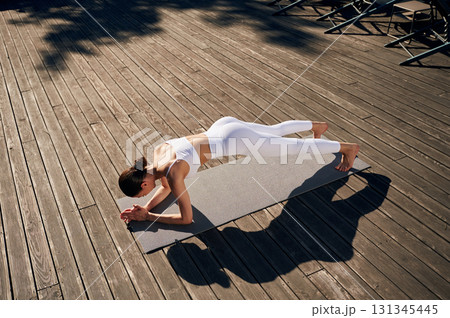 Plank exercise. Young woman in fitness clothes is outdoors 131345445