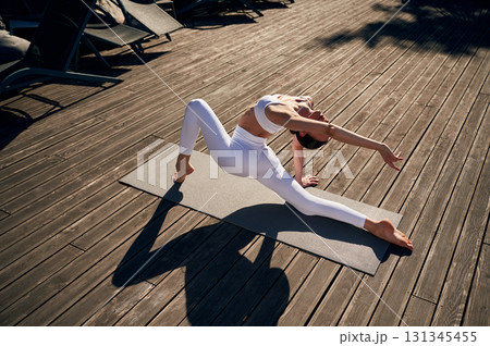 Exercises for flexibility. Young woman in fitness clothes is outdoors Exercises for flexibility. Young woman in fitness clothes is outdoors 131345455