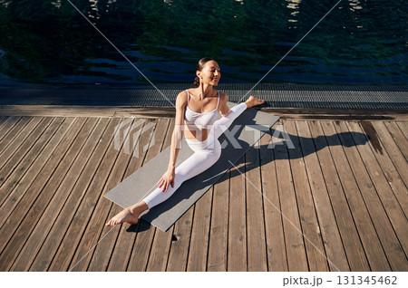 Makes twine. Young woman in fitness clothes is outdoors Makes twine. Young woman in fitness clothes is outdoors 131345462