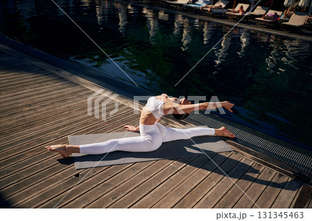 Makes twine. Young woman in fitness clothes is outdoors Makes twine. Young woman in fitness clothes is outdoors 131345463