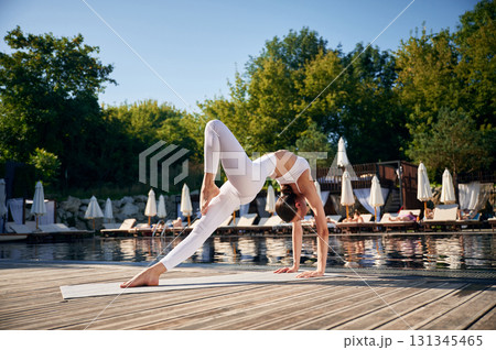 Spine exercises. Young woman in fitness clothes is outdoors Spine exercises. Young woman in fitness clothes is outdoors 131345465