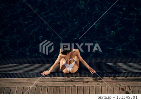 Near swimming pool. Woman in white bikini 131345501