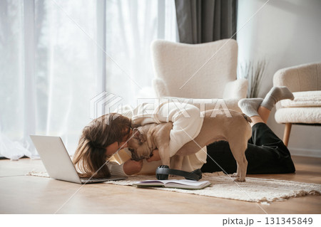 Wooden floor. With laptop. Young woman is with her pug dog at home Wooden floor. With laptop. Young woman is with her pug dog at home 131345849