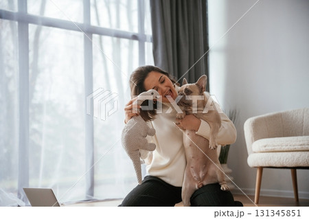 Conception of love and care. Young woman is with her pug dog at home Conception of love and care. Young woman is with her pug dog at home 131345851
